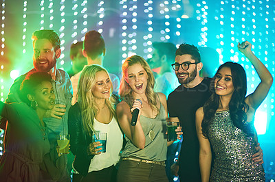 Buy stock photo Shot of a group of friends singing karaoke at a party