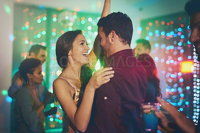 Buy stock photo Shot of an affectionate young couple dancing on a crowded dance floor in a nightclub
