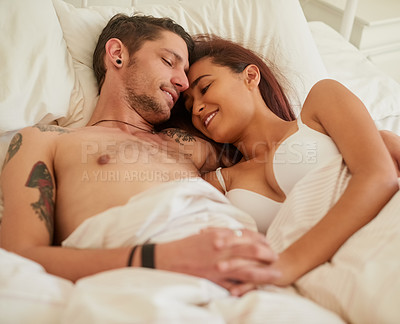Buy stock photo Shot of an affectionate young couple cuddling in their bed at home
