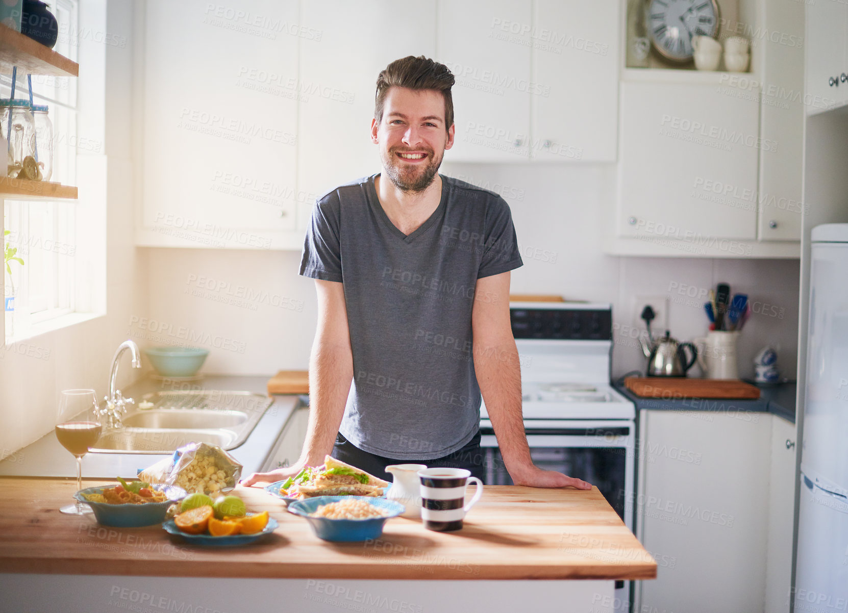 Buy stock photo Portrait of a handsome young man standing in front of meals which he has prepared in his kitchen