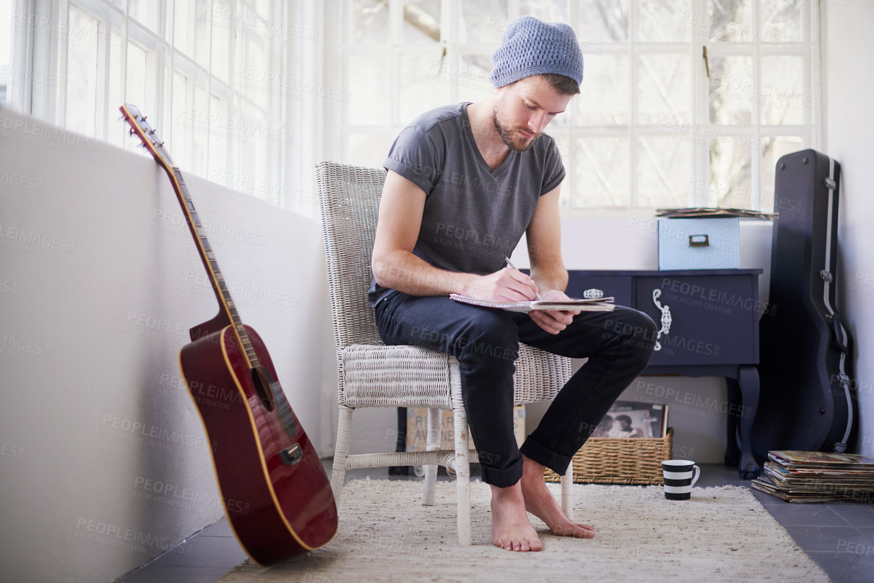Buy stock photo Shot of a handsome young man writing his own song at home