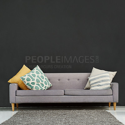 Buy stock photo Shot of a gray sofa with cushions against a black background