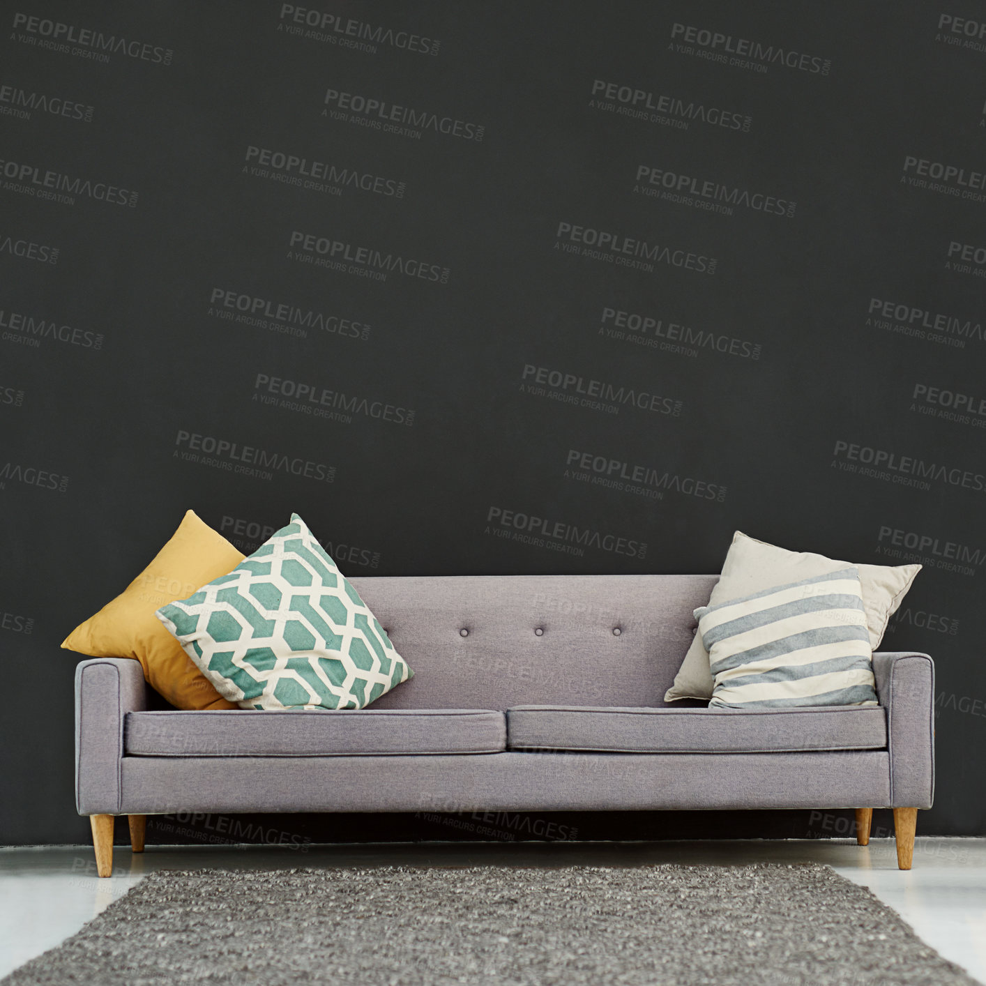 Buy stock photo Shot of a gray sofa with cushions against a black background