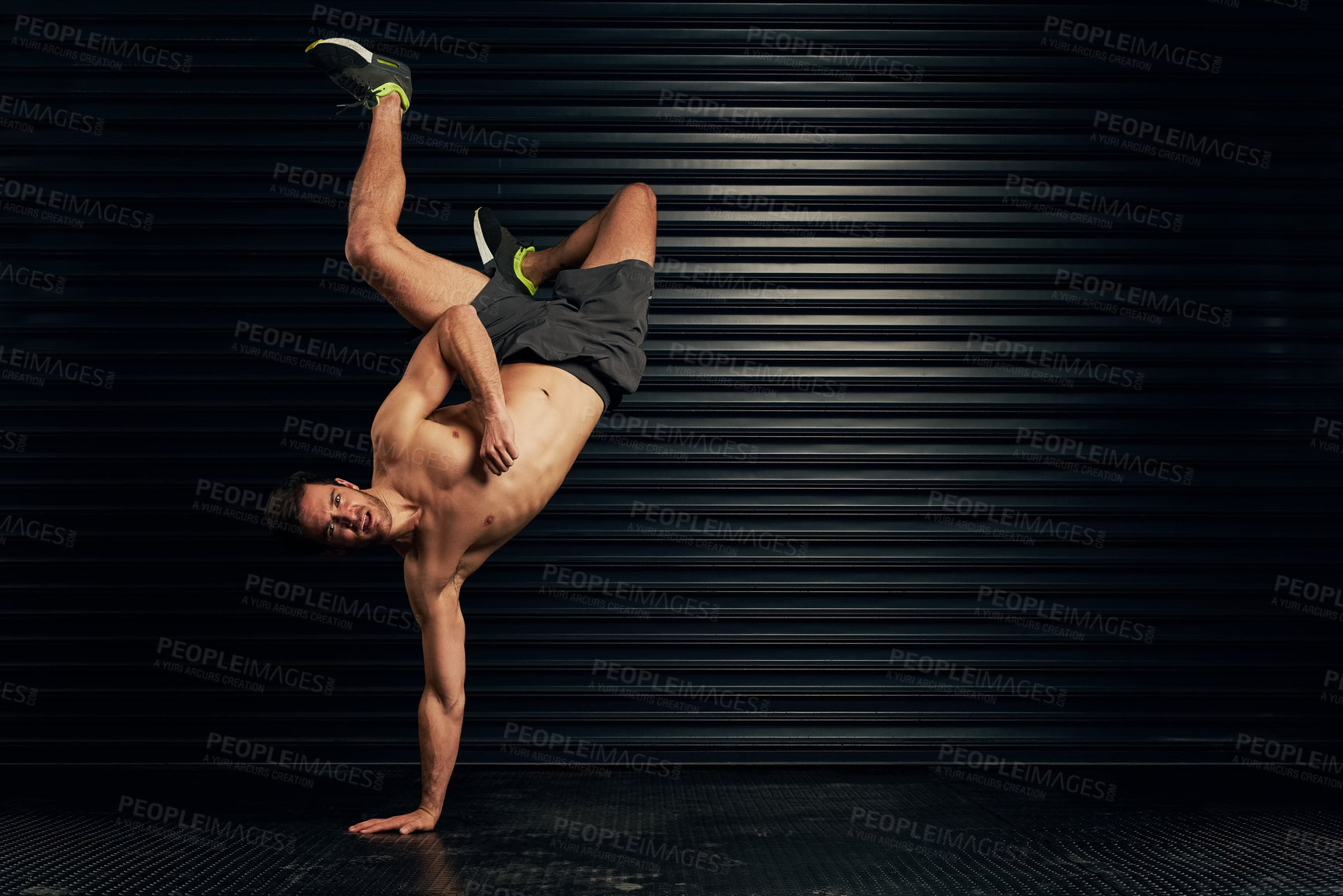 Buy stock photo Studio portrait of a shirtless and well built man breakdancing against a dark background