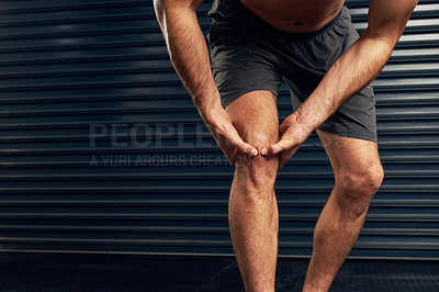 Buy stock photo Studio shot of an unrecognizable holding his knee against a dark background