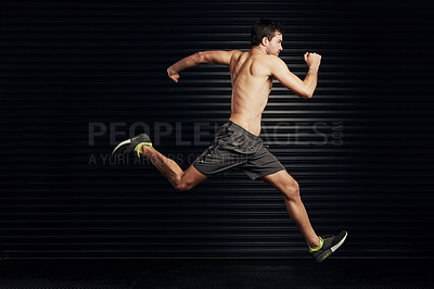 Buy stock photo Studio shot of a shirtless and well built man sprinting against a dark background