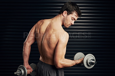Buy stock photo Studio shot of a shirtless and well built man lifting dumbbells warming up against a dark background