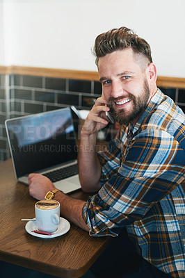Buy stock photo Portrait of a young man using his cellphone and laptop while sitting in a cafe