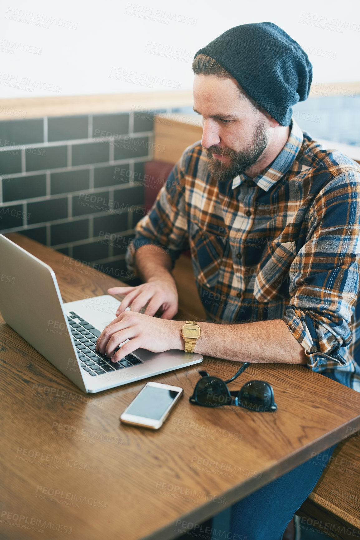 Buy stock photo Shot of a young man using his laptop while sitting in a cafe