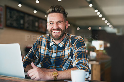 Buy stock photo Portrait of a young man using his laptop while sitting by the window in a cafe