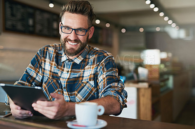 Buy stock photo Portrait of a young man using his tablet while sitting by the window in a cafe
