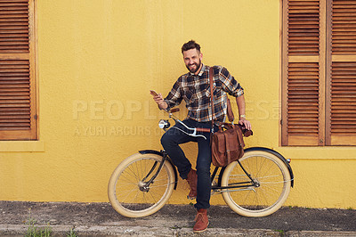 Buy stock photo Portrait of a young man using his cellphone while standing outside with his bicycle