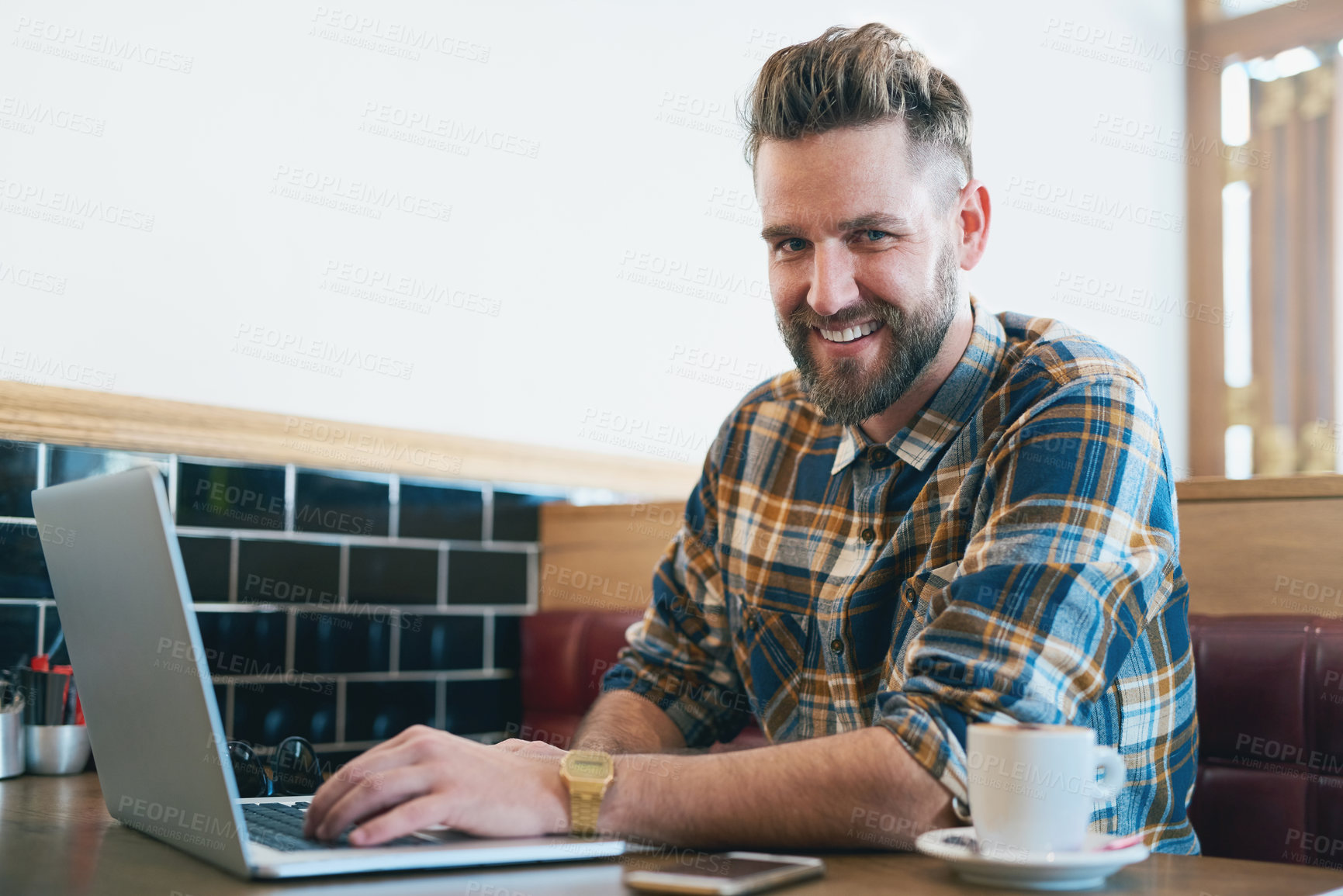 Buy stock photo Portrait of a young man using his laptop while sitting in a cafe