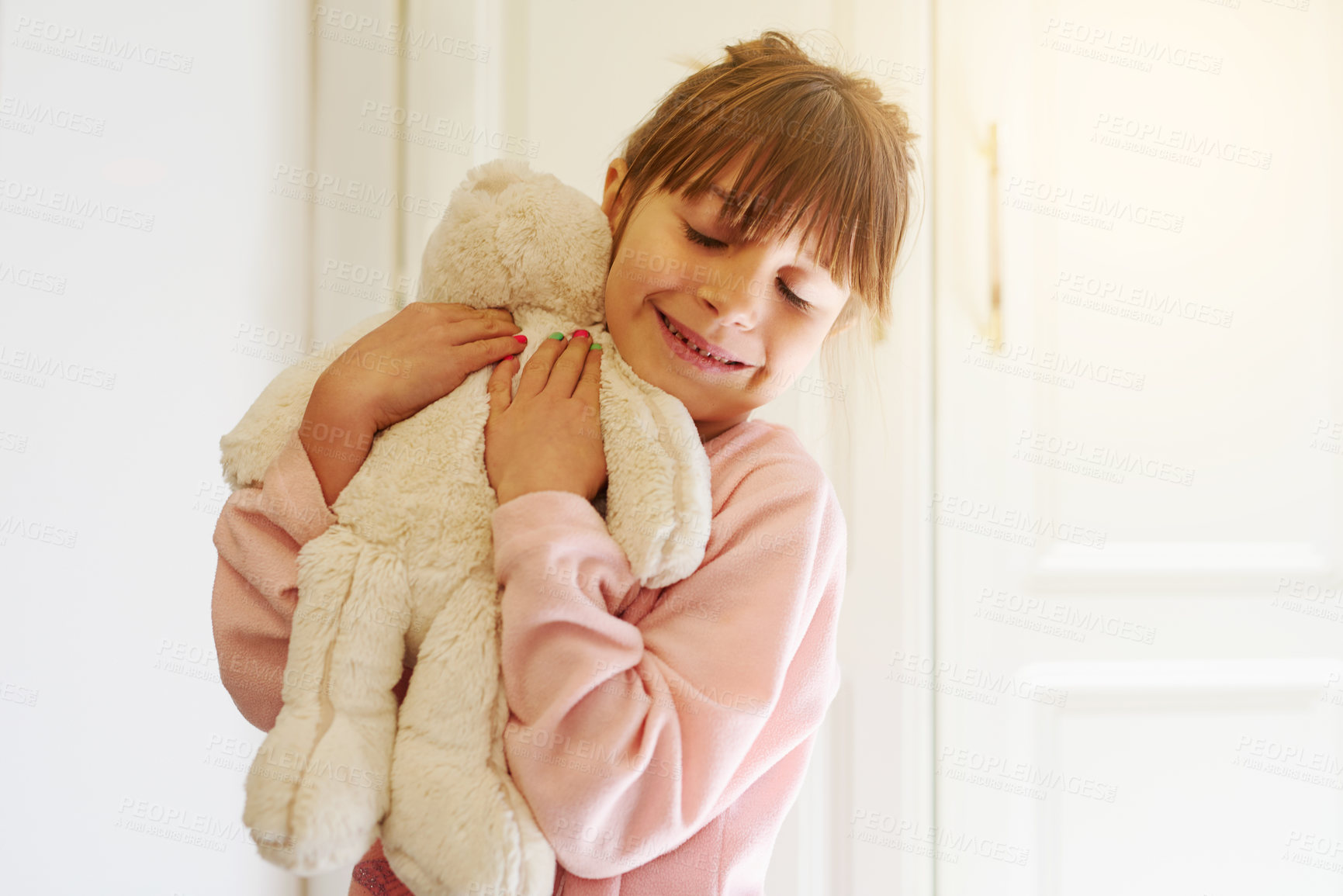 Buy stock photo Happy girl, hug and love with teddy bear for comfort, soft toy or playful doll at home. Little child or kid with smile for cuddle, warmth or cute stuffy in embrace for childhood or youth at house
