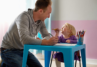 Buy stock photo Cropped shot of a father and daughter colouring in together at home