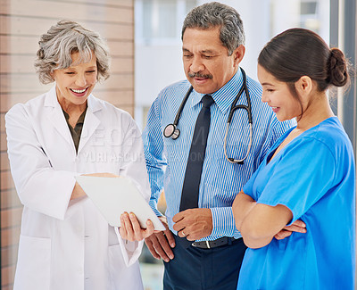 Buy stock photo Shot of three healthcare professionals looking over medical records on a tablet