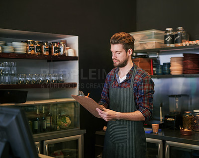 Buy stock photo Cropped shot of a young cafe owner doing stock take
