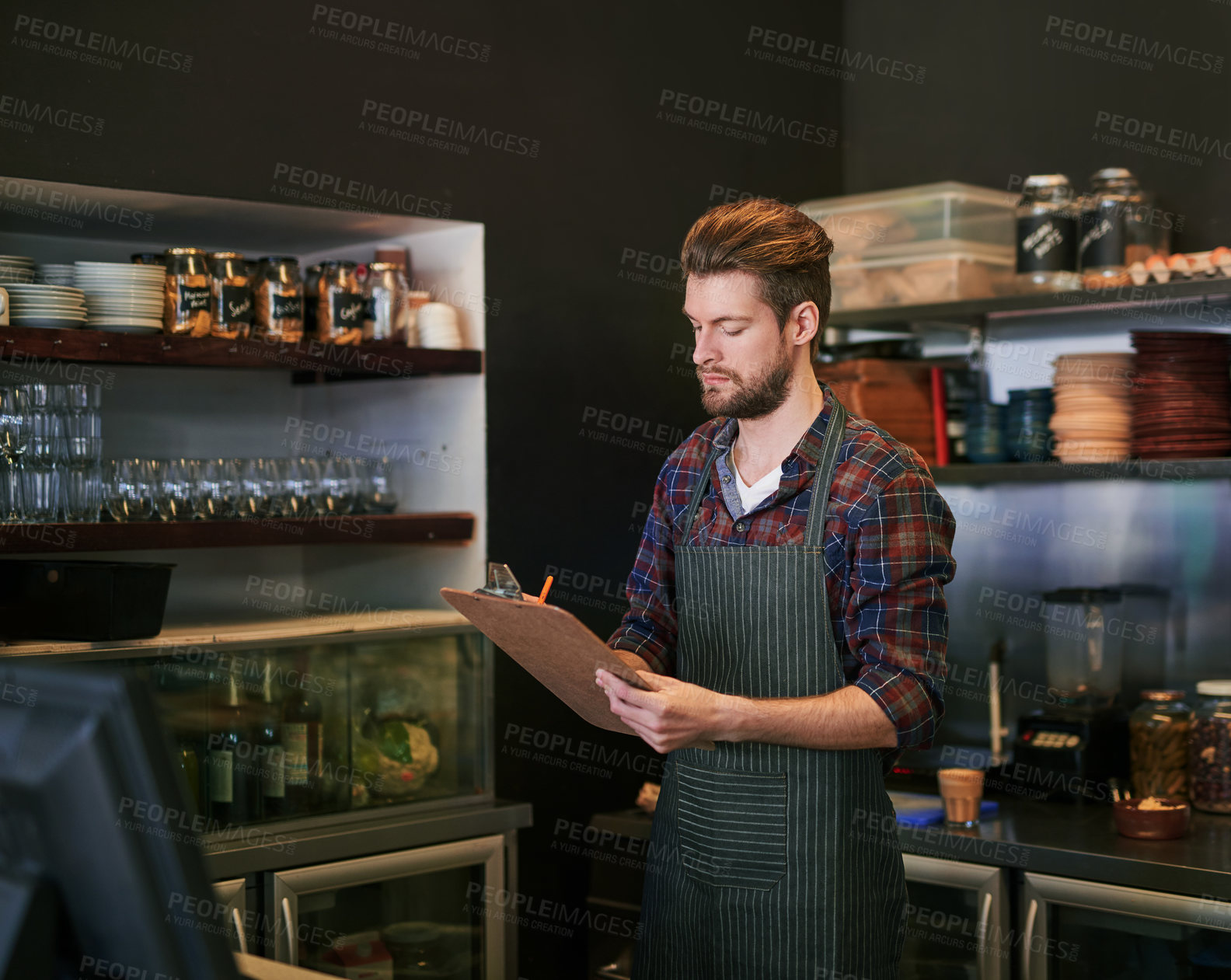 Buy stock photo Cropped shot of a young cafe owner doing stock take