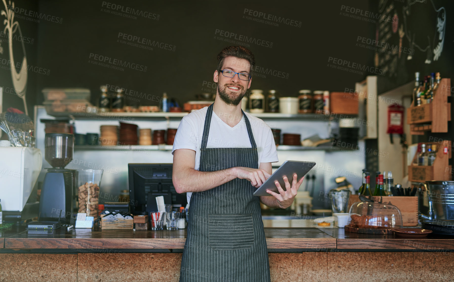 Buy stock photo Cropped portrait of a young barista using a tablet in his coffee shop