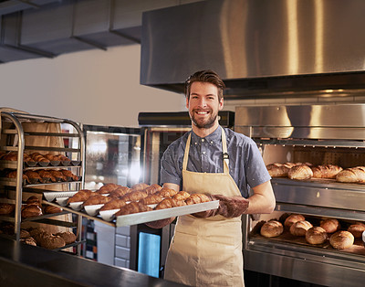 Buy stock photo Cropped shot of a man taking out a fresh batch of croissants to serve to his customers