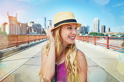 Buy stock photo Shot of a smiling young woman walking around the city in the summertime