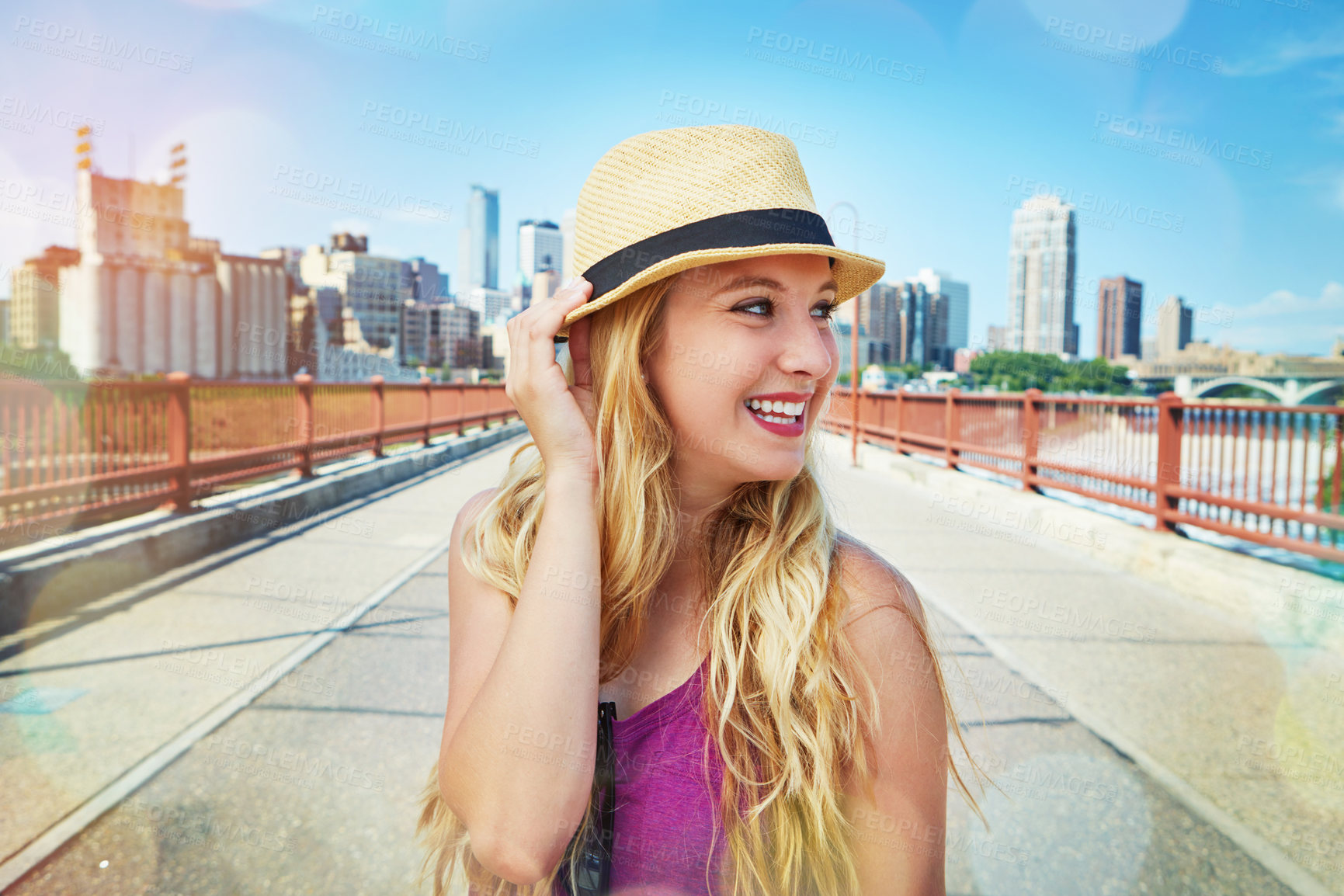 Buy stock photo Shot of a smiling young woman walking around the city in the summertime