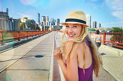 Buy stock photo Shot of a smiling young woman walking around the city in the summertime