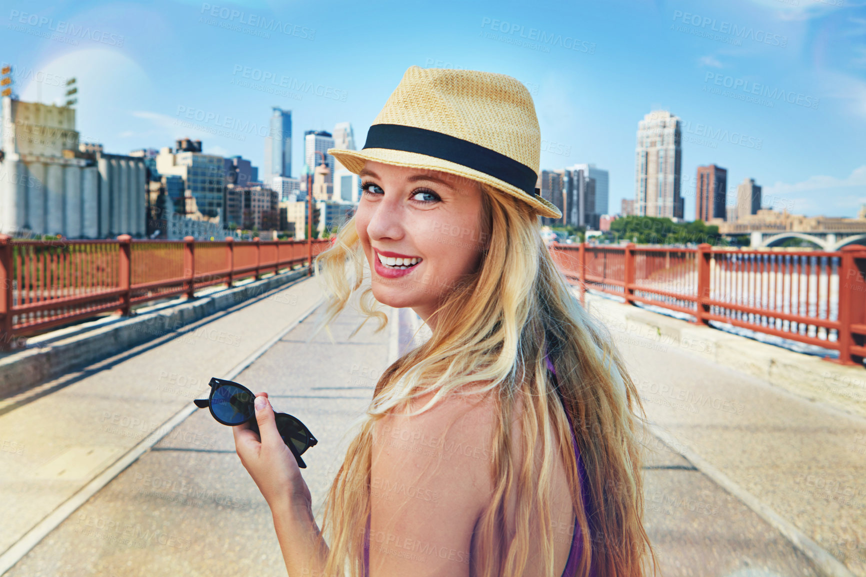 Buy stock photo Shot of a smiling young woman walking around the city in the summertime