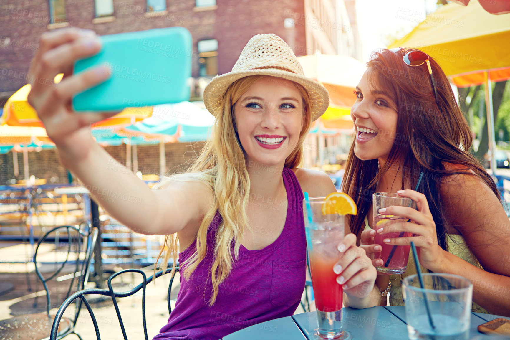 Buy stock photo Shot of two attractive young women taking a selfie while sitting at an outdoor cafe