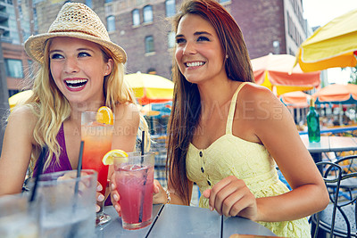 Buy stock photo Shot of two attractive young women sitting at an outdoor cafe