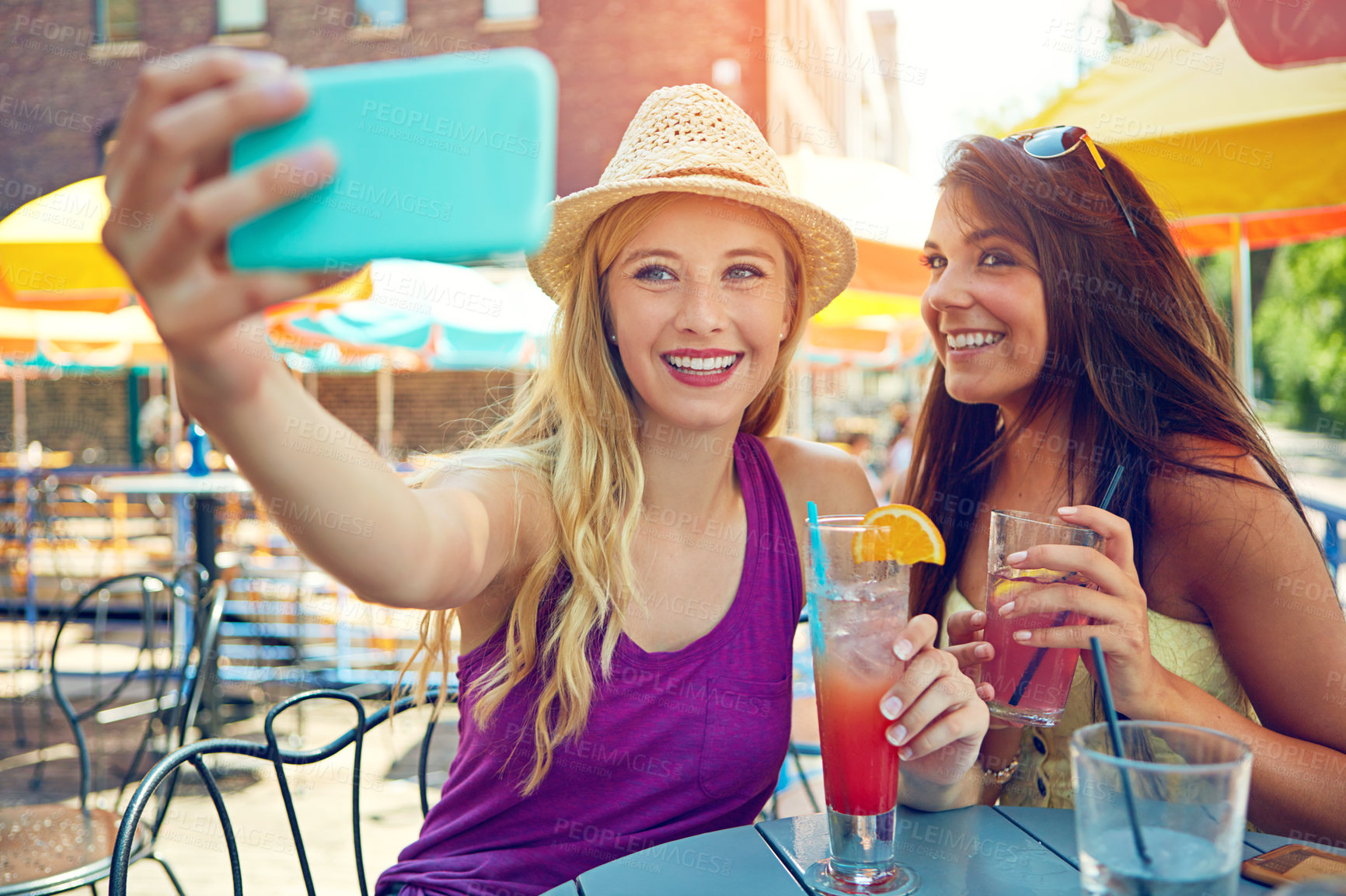 Buy stock photo Shot of two attractive young women taking a selfie while sitting at an outdoor cafe