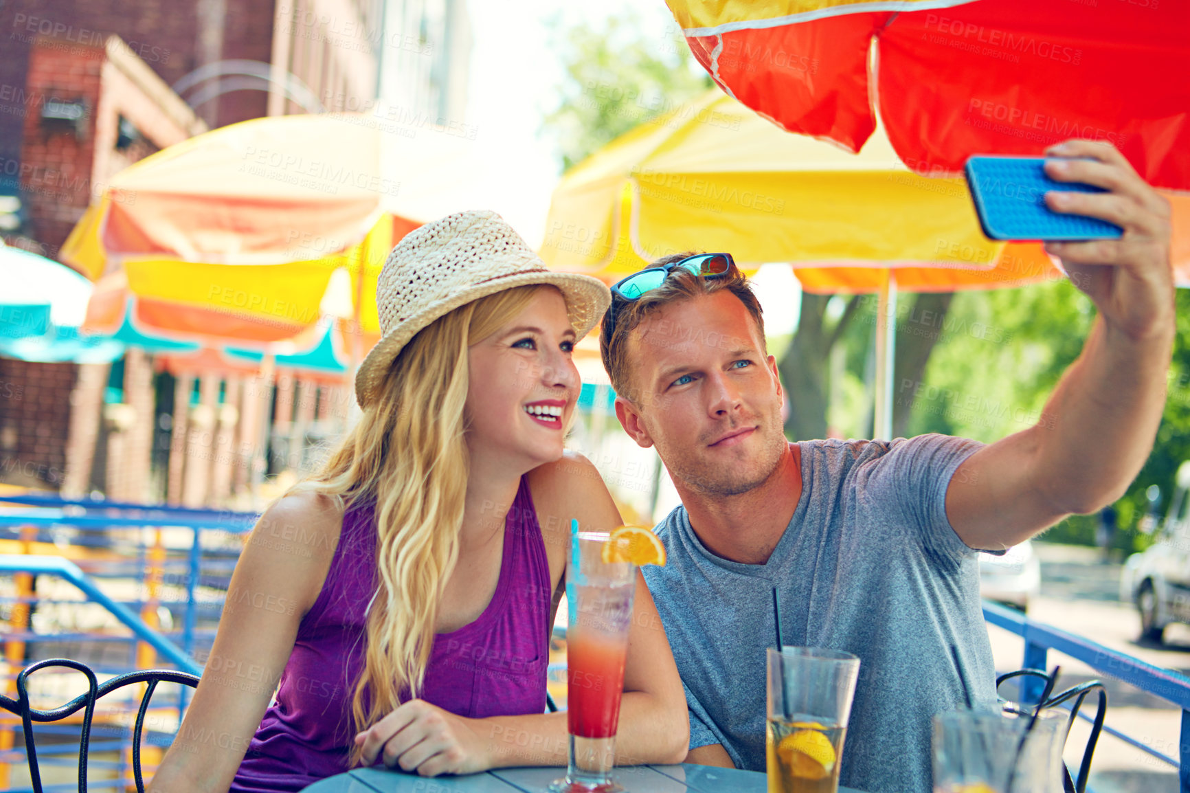 Buy stock photo Shot of a young couple taking a selfie while sitting at an outdoor cafe