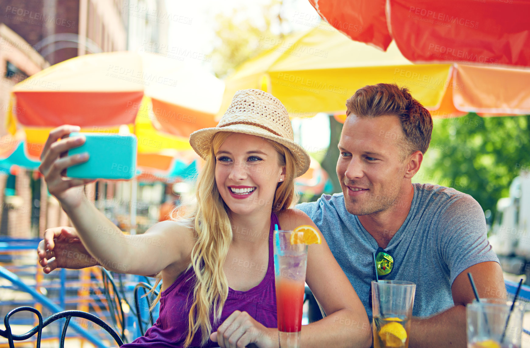 Buy stock photo Shot of a young couple taking a selfie while sitting at an outdoor cafe