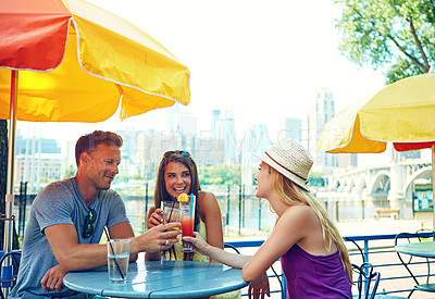 Buy stock photo Shot of three young friends sitting at an outdoor cafe