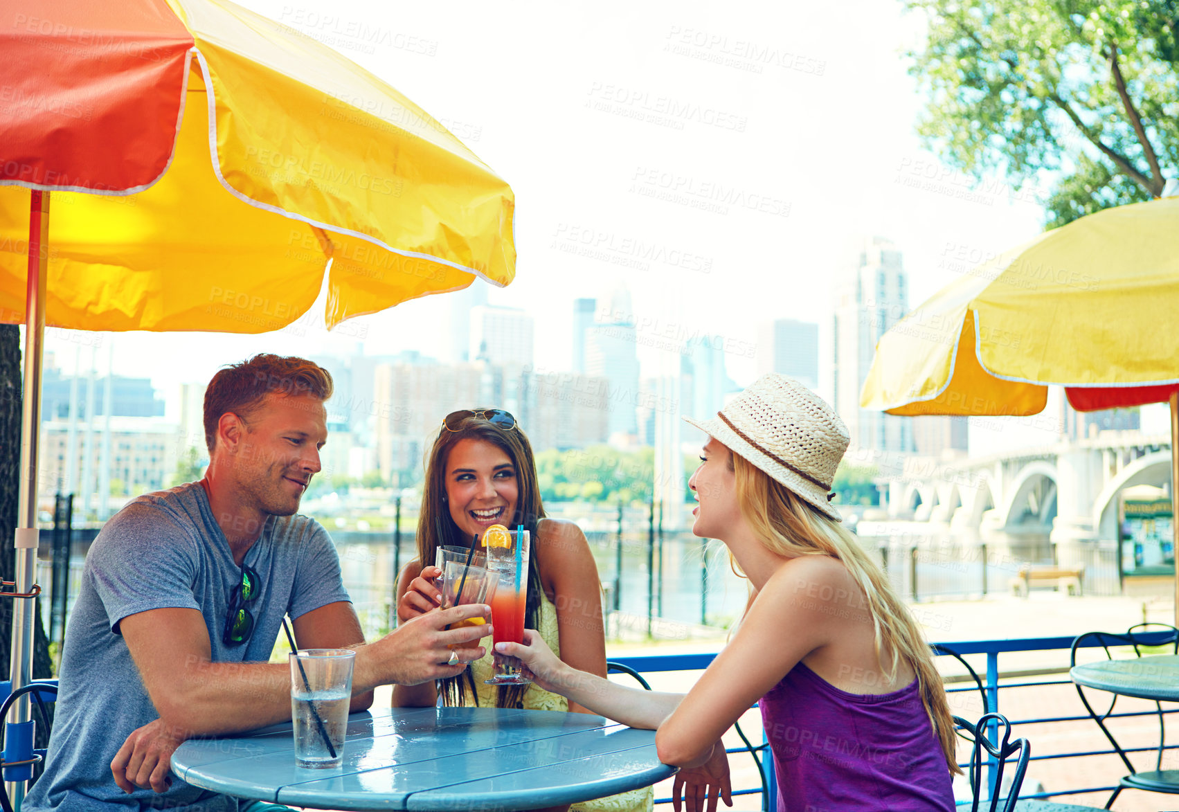 Buy stock photo Shot of three young friends sitting at an outdoor cafe