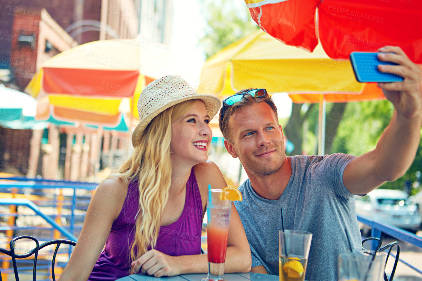 Buy stock photo Shot of a young couple taking a selfie while sitting at an outdoor cafe