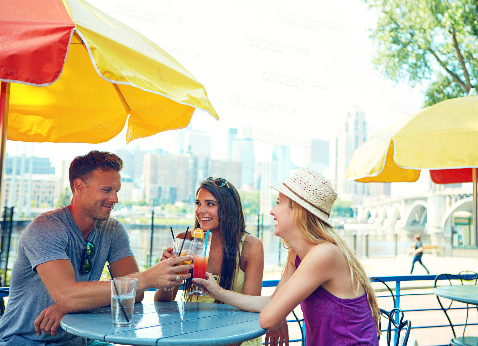 Buy stock photo Shot of three young friends sitting at an outdoor cafe