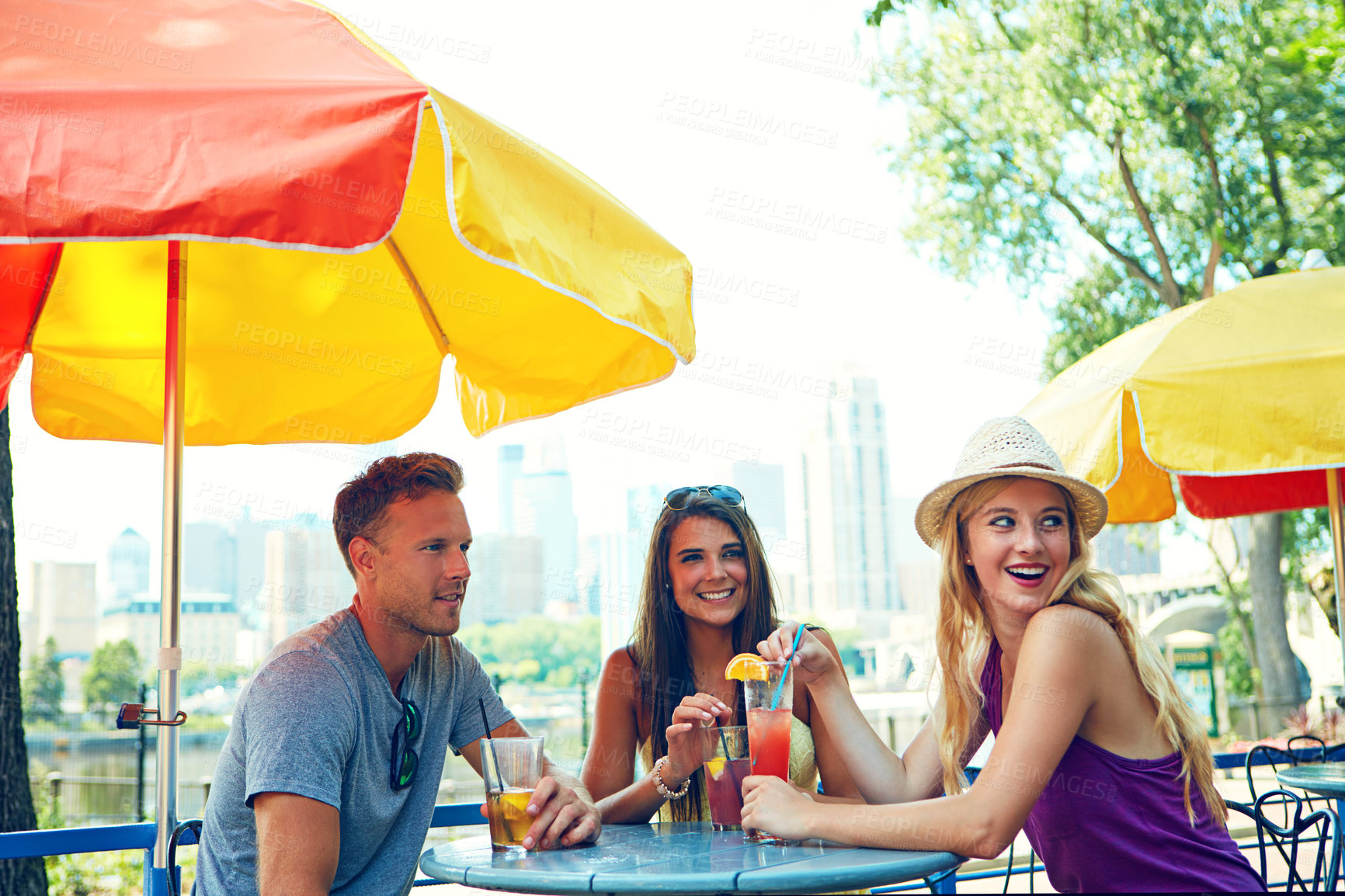 Buy stock photo Shot of three young friends sitting at an outdoor cafe