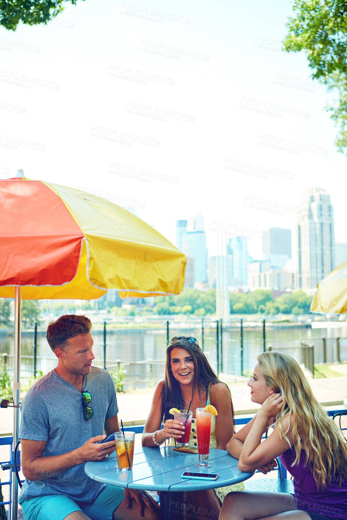 Buy stock photo Shot of three young friends sitting at an outdoor cafe