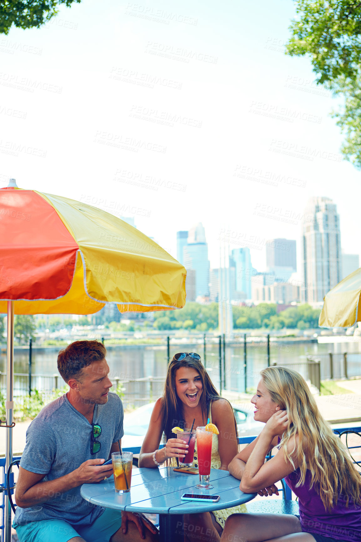 Buy stock photo Shot of three young friends sitting at an outdoor cafe