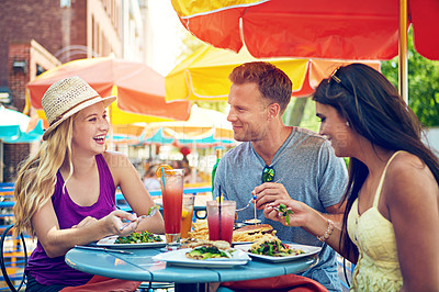 Buy stock photo Shot of three young friends sitting at an outdoor cafe