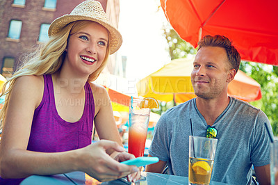 Buy stock photo Shot of a young couple sitting at an outdoor cafe