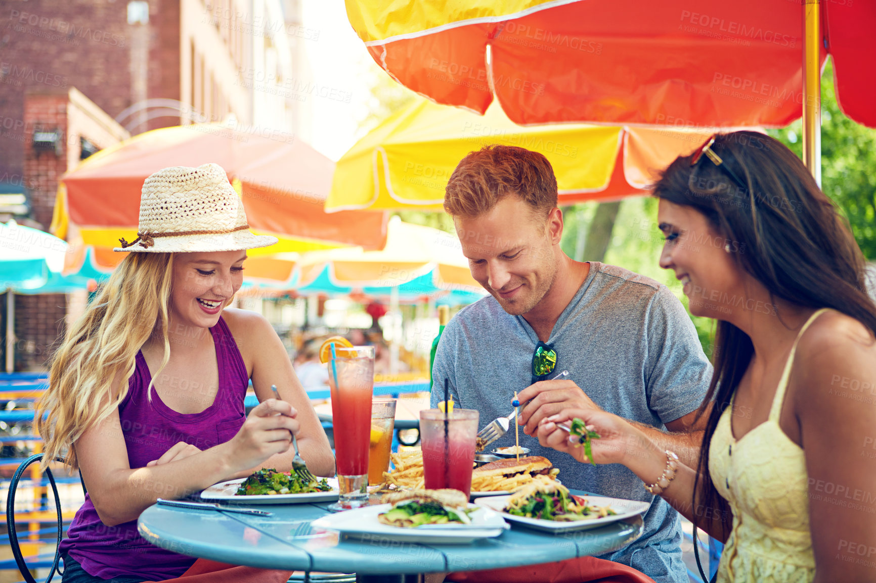 Buy stock photo Shot of three young friends sitting at an outdoor cafe