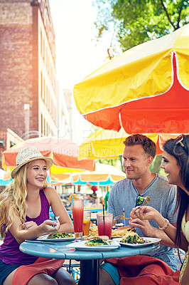 Buy stock photo Shot of three young friends sitting at an outdoor cafe