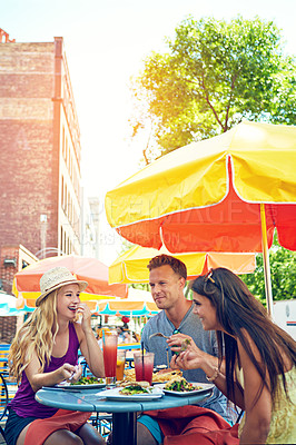 Buy stock photo Shot of three young friends sitting at an outdoor cafe