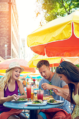 Buy stock photo Shot of three young friends sitting at an outdoor cafe