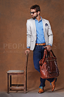 Buy stock photo Bag, chair and confident man with clothes for fashion, style and formal wear isolated on studio background. Male person, gentleman and businessman with trendy outfit, class or suit in brown backdrop
