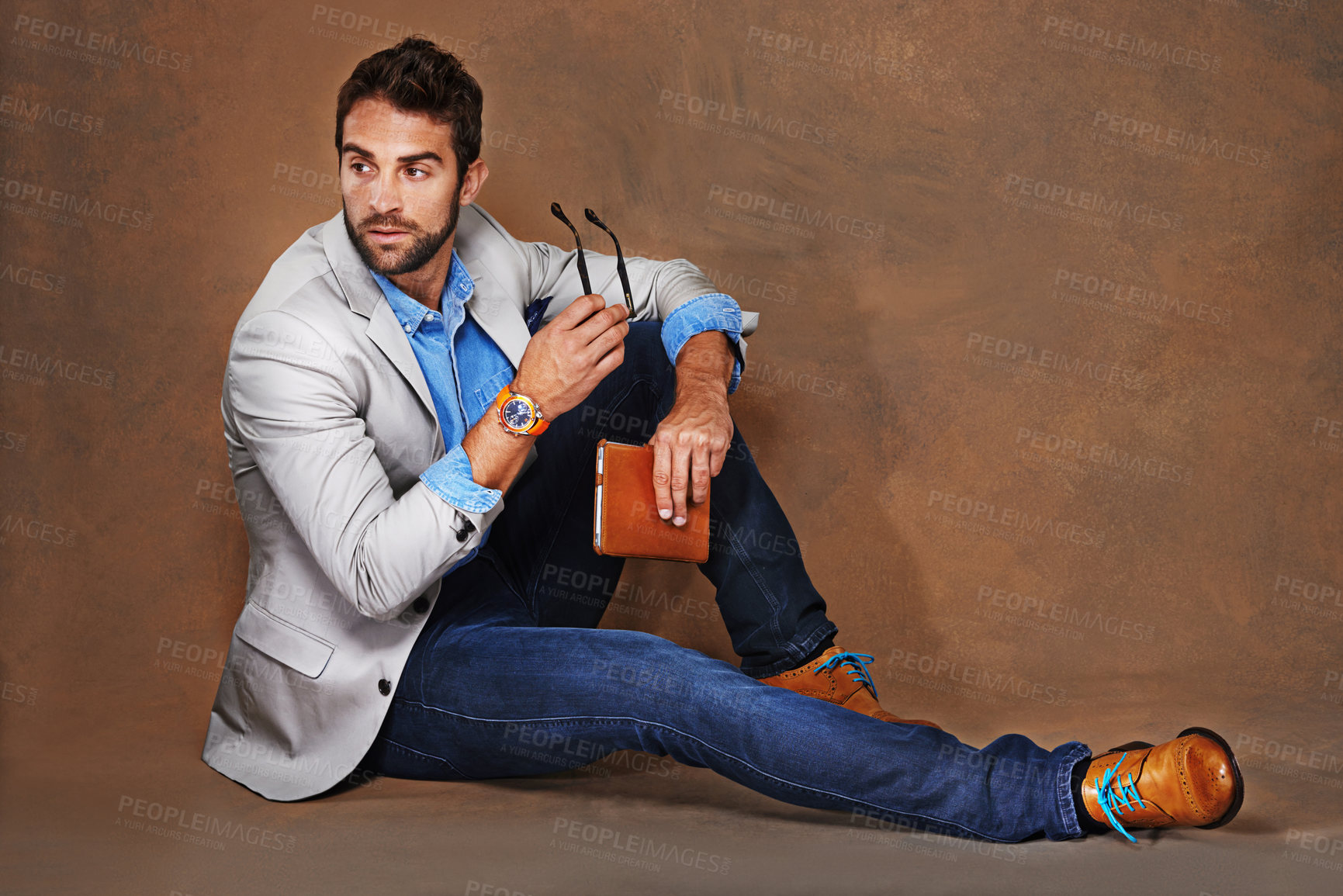 Buy stock photo Style, book and man with glasses in studio with trendy, stylish and classy suit on floor. Reading, story and handsome male person with elegant fashion for outfit and novel by brown background.