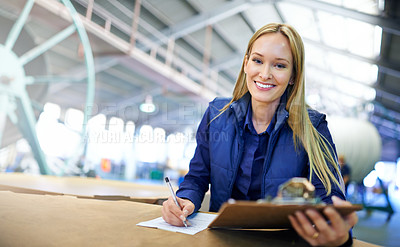 Buy stock photo Portrait of a smiling manager reading paperwork while standing on the factory floor