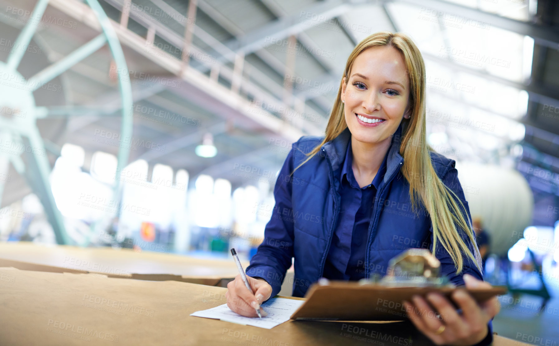 Buy stock photo Portrait of a smiling manager reading paperwork while standing on the factory floor